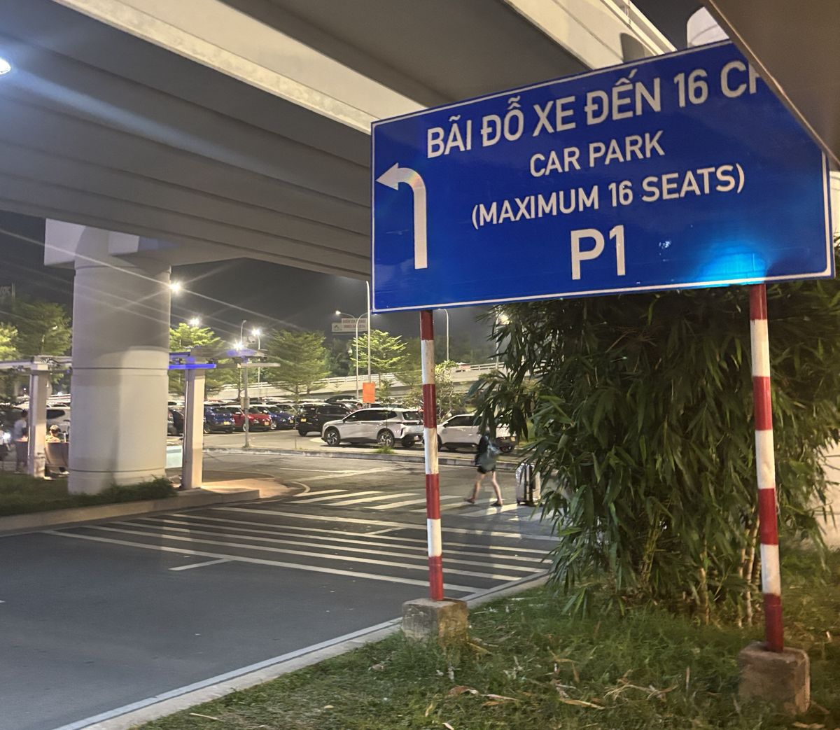 Blue sign at Hanoi Noi Bai airport pointing left to Car Park P1, with the parking lot behind it