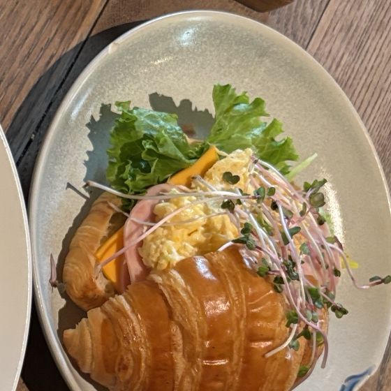 Croissant with scrambled eggs, bacon and salad