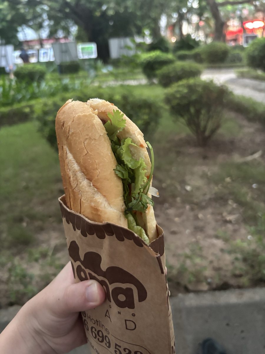A Mama banh mi in its paper bag, packed with herbs and lettuce